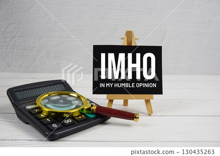 IMHO abbreviation of In My Humble Opinion text with magnifying glass and calculator on wooden background IMHO abbreviation of In My Humble Opinion text with magnifying glass and calculator on wooden background 130435263
