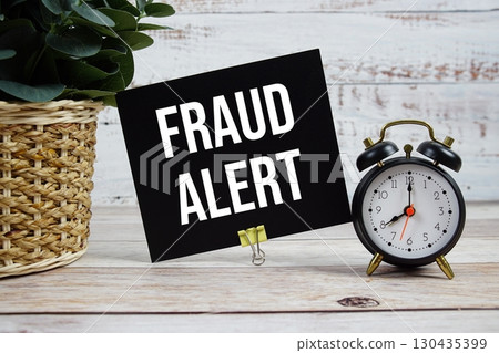 Fraud Alert text with alarm clock on wooden background 130435399