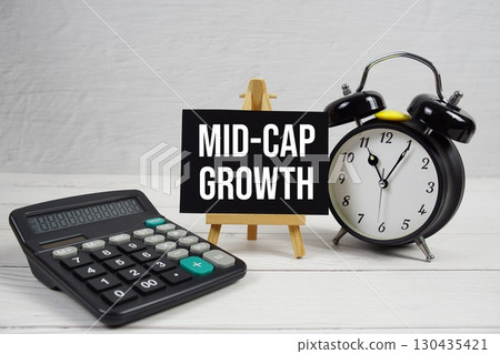 Mid-Cap Growth text with alarm clock and calculator on wooden background Mid-Cap Growth text with alarm clock and calculator on wooden background 130435421