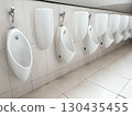 Row of white ceramic urinals in a public restroom, clean and organized sanitary facility with tiled walls and floor, representing hygiene, infrastructure, and modern bathroom interior design 130435455