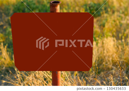 Red frame for text on an old pipe in a field with dry grass 130435633
