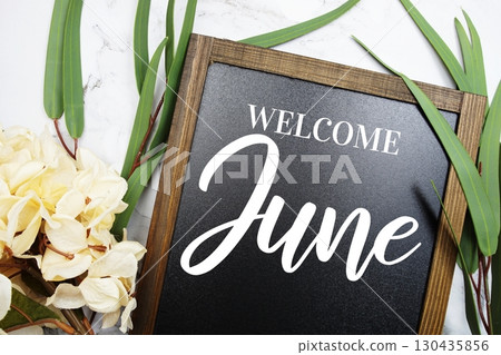 Welcome June text on blackboard with flowers decorated on marble background 130435856