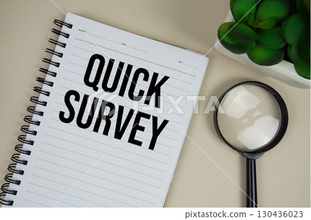 Quick Survey text on paper notebook with magnifying glass on beige leather background 130436023