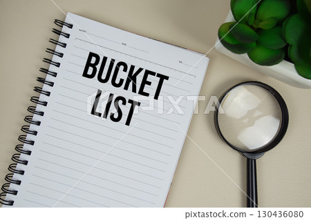 Bucket List text on paper notebook with magnifying glass on beige leather background 130436080