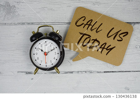 Call Us Today text with alarm clock on wooden background Call Us Today text with alarm clock on wooden background 130436138