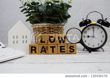 LOW RATES alphabet letters with house model, alarm clock and magnifying glass on wooden background 130436170