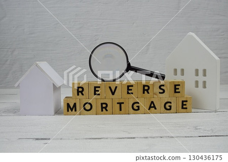 Reverse Mortgage alphabet letters with house model and magnifying glass on wooden background 130436175