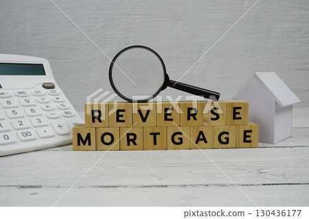 Reverse Mortgage alphabet letters with house model, calculator and magnifying glass on wooden background 130436177