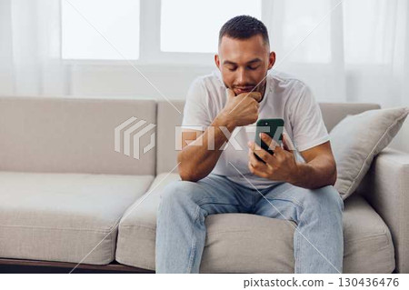 Thoughtful man browsing his phone, reflecting on digital connections and personal growth in the realm of mental health, anxiety, and modern living. Thoughtful man browsing his phone, reflecting on digital connections and personal growth in the realm of mental health, anxiety, and modern living. 130436476