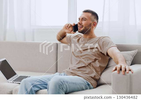 A relaxed man talking on the phone while sitting comfortably on a couch, symbolizing the blend of personal and professional life amidst digital detox. A relaxed man talking on the phone while sitting comfortably on a couch, symbolizing the blend of personal and professional life amidst digital detox. 130436482