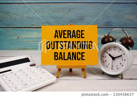 Average Outstanding Balance text written on paper card with calculator and alarm clock on wooden background Average Outstanding Balance text written on paper card with calculator and alarm clock on wooden background 130436637