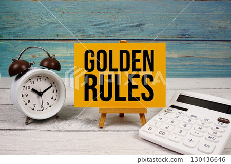 Golden Rules text written on paper card with calculator and alarm clock on wooden background Golden Rules text written on paper card with calculator and alarm clock on wooden background 130436646