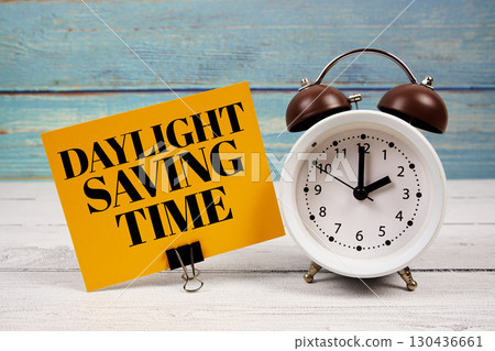Daylight Saving Time text written on paper card with alarm clock on wooden background Daylight Saving Time text written on paper card with alarm clock on wooden background 130436661