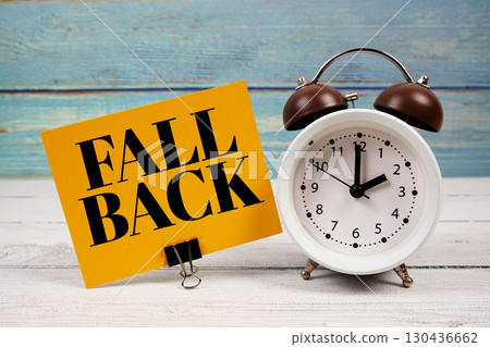 Fall Back text written on paper card with alarm clock on wooden background Fall Back text written on paper card with alarm clock on wooden background 130436662