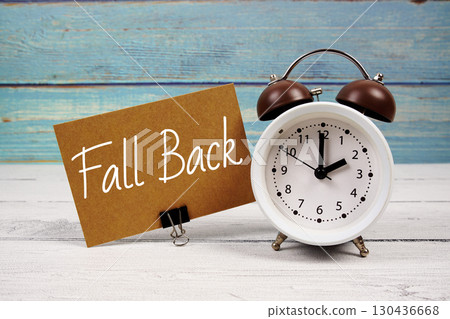 Fall Back  text written on paper card with alarm clock on wooden background 130436668