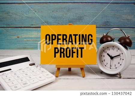 Operating Profit text written on paper card with calculator and alarm clock on wooden background Operating Profit text written on paper card with calculator and alarm clock on wooden background 130437042