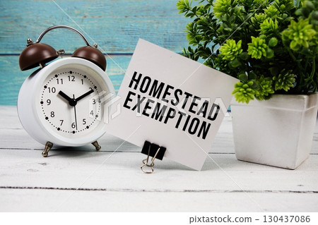 Homestead Exemption text written on paper card with alarm clock on wooden background Homestead Exemption text written on paper card with alarm clock on wooden background 130437086