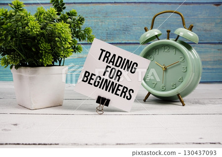 Trading For Beginners text written on paper card with alarm clock on wooden background 130437093