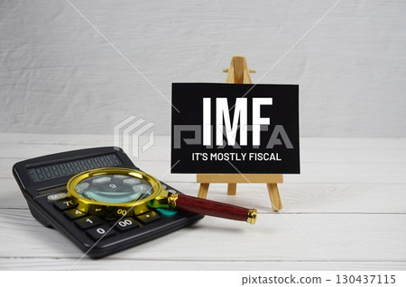 IMF abbreviation of It's Mostly Fiscal text with magnifying glass and calculator on wooden background IMF abbreviation of It's Mostly Fiscal text with magnifying glass and calculator on wooden background 130437115