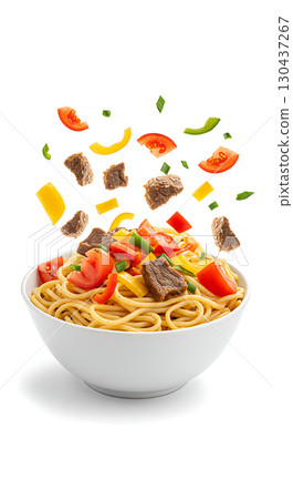 A white bowl filled with spaghetti, topped with chunks of beef, tomato slices, yellow bell pepper, and green onions. Ingredients appear to be floating above the bowl 130437267