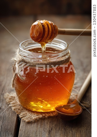 Golden honey in jar with wooden dipper on rustic table 130437883