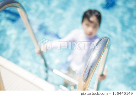 Girl climbing a ladder by the pool 130440149
