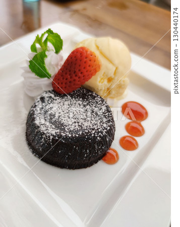 Indulgent chocolate lava cake dessert with scoop of ice cream and fresh strawberry on white plate. delicious sweet treat with melted center, perfect for satisfying Indulgent chocolate lava cake dessert with scoop of ice cream and fresh strawberry on white plate. delicious sweet treat with melted center, perfect for satisfying 130440174