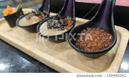 Salmon roe and creamy sauce served in black spoons on wooden tray, showcasing fresh and vibrant seafood appetizer with delicate texture and rich flavor Salmon roe and creamy sauce served in black spoons on wooden tray, showcasing fresh and vibrant seafood appetizer with delicate texture and rich flavor 130440261
