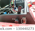 Focused closeup on an electronic device during repair in workshop. equipment features black knob, switch, and internal wire, showing complex technology 130440273