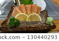 Appetizing fresh salmon sashimi on ice with lemon and wasabi. delicious raw fish meal from Japanese cuisine served on dark plate. healthy seafood appetizer for dinner 130440293
