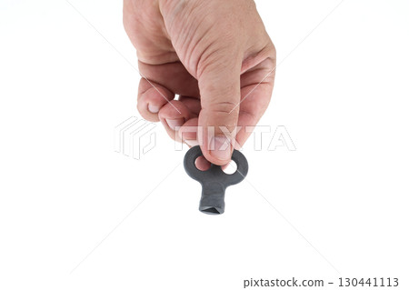 Hand Holding a Small Winding Key Isolated on White Background Hand Holding a Small Winding Key Isolated on White Background 130441113