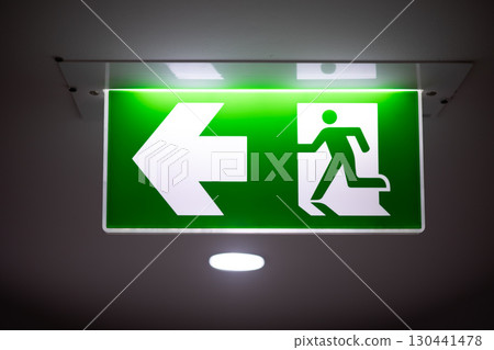 Exit way arrow direction guidance sign green color light emergency exit sign in a dark room 130441478
