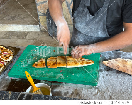 Freshly baked flatbread stuffed with meat being cut and served. Street food, traditional cuisine and authentic local flavors. 130441629