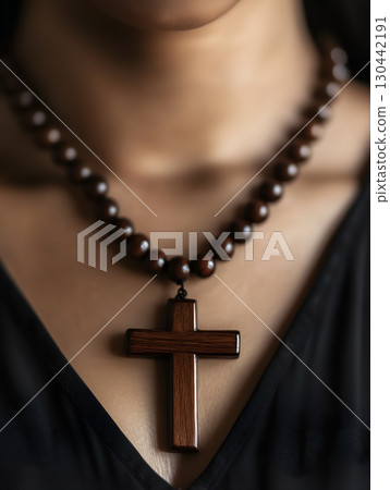Person praying with a wooden rosary and crucifix to express faith and devotion 130442191