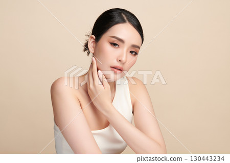 A beautiful young Asian woman with clean, fresh skin against a beige background. Skincare, facial treatment, cosmetology, beauty, and spa. An elegant portrait of an Asian woman. A beautiful young Asian woman with clean, fresh skin against a beige background. Skincare, facial treatment, cosmetology, beauty, and spa. An elegant portrait of an Asian woman. 130443234