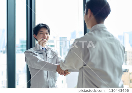 Men in work clothes shaking hands 130443496