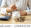Image of putting coins in a piggy bank and calculating 130443530