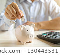 Image of putting coins in a piggy bank and calculating 130443531