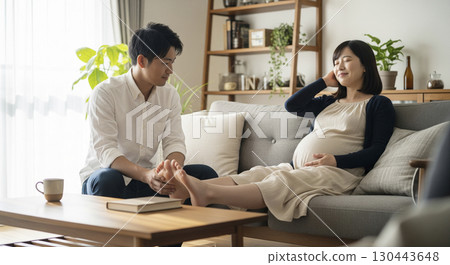 Husband massaging the feet of a pregnant woman lying on the sofa Husband massaging the feet of a pregnant woman lying on the sofa 130443648