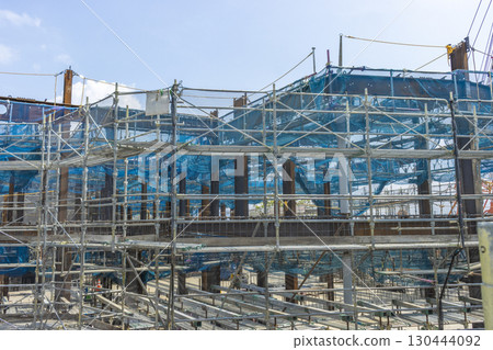 Scaffolding and blue sky around the perimeter of a reinforced concrete building under construction 130444092