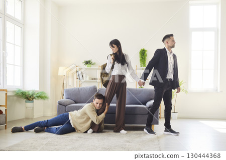 Emotional scene with desperate man clinging to woman leaving with another man Emotional scene with desperate man clinging to woman leaving with another man 130444368