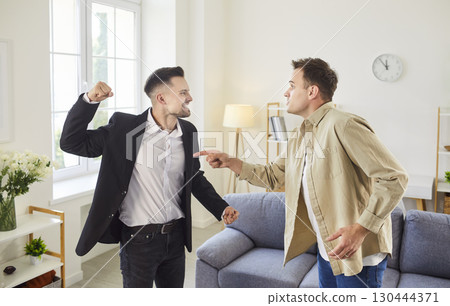 Two angry men are in a heated argument with intense expressions in living room 130444371