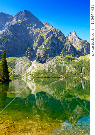 landscape with lake in mountains. scenic nature of poland with rocky peaks in summer. high tatras are wonderful place for travel in eastern europe landscape with lake in mountains. scenic nature of poland with rocky peaks in summer. high tatras are wonderful place for travel in eastern europe 130444435