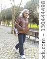 Senior woman walking in park enjoying retirement 130444498