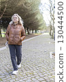 Senior woman enjoying walk in park during daytime 130444500