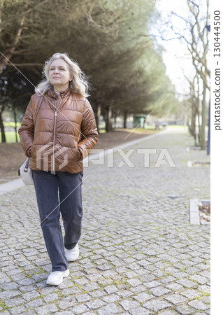 Senior woman enjoying walk in park during daytime Senior woman enjoying walk in park during daytime 130444500