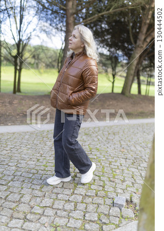 Senior woman walking in park enjoying sunny day 130444502