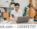 stressed woman working with smartphone and laptop computer at home office 130445797
