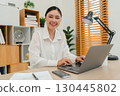 happy woman working with laptop computer at home office 130445802