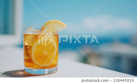 A glass of lemon iced tea with a summer blue sky and sea in the background_1 130445819